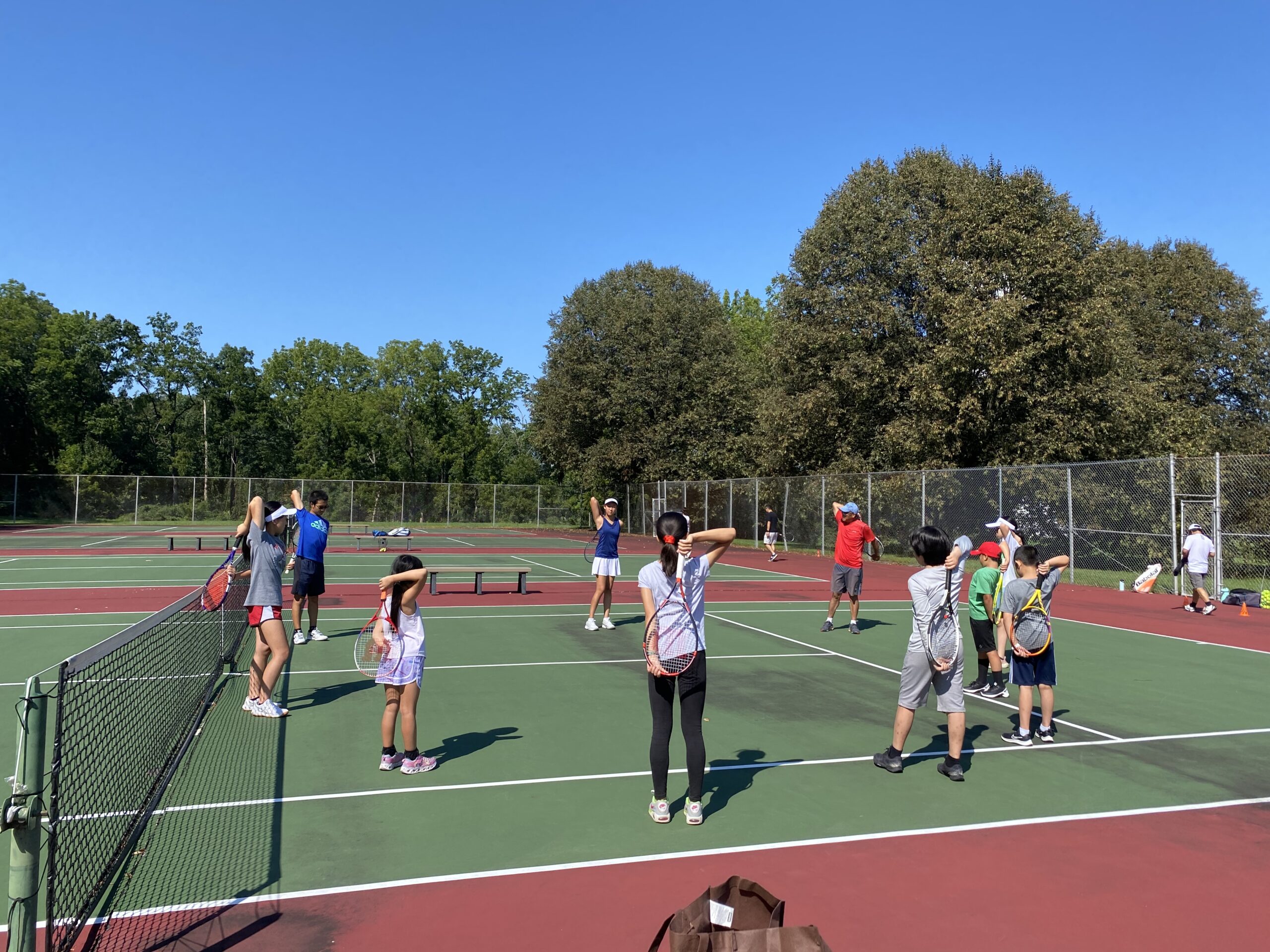 Fall 2023 tennis players warming up together across the courts