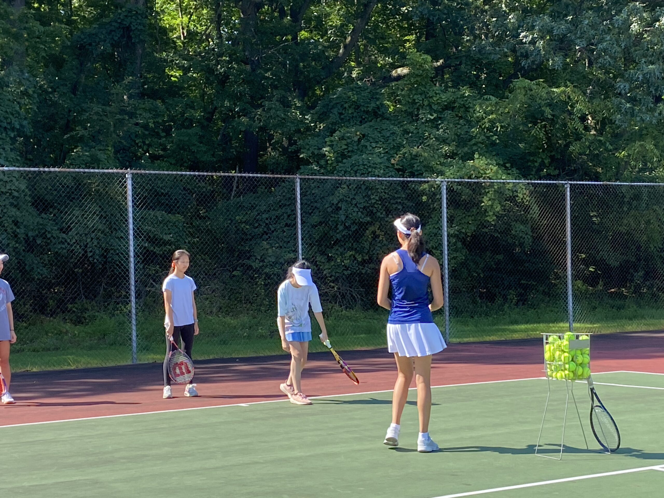 Fall tennis club instruction with a basket of practice balls