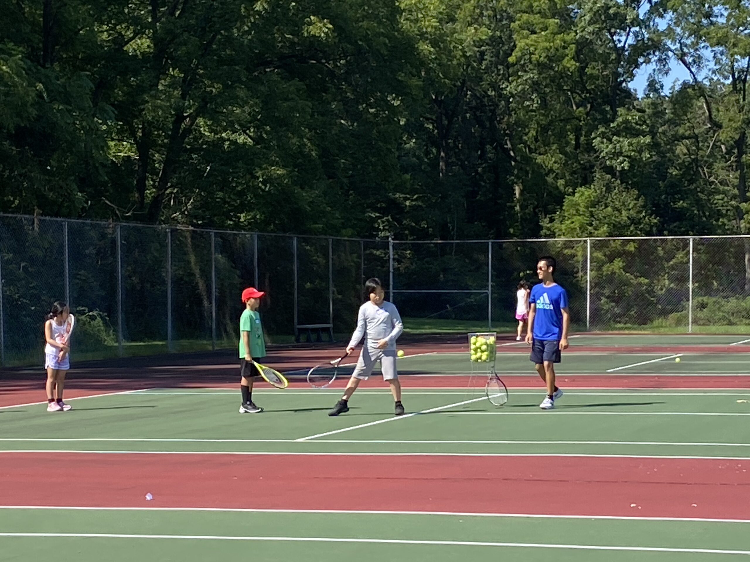 Coach Derek Yao practicing with students during the 2023 fall tennis club