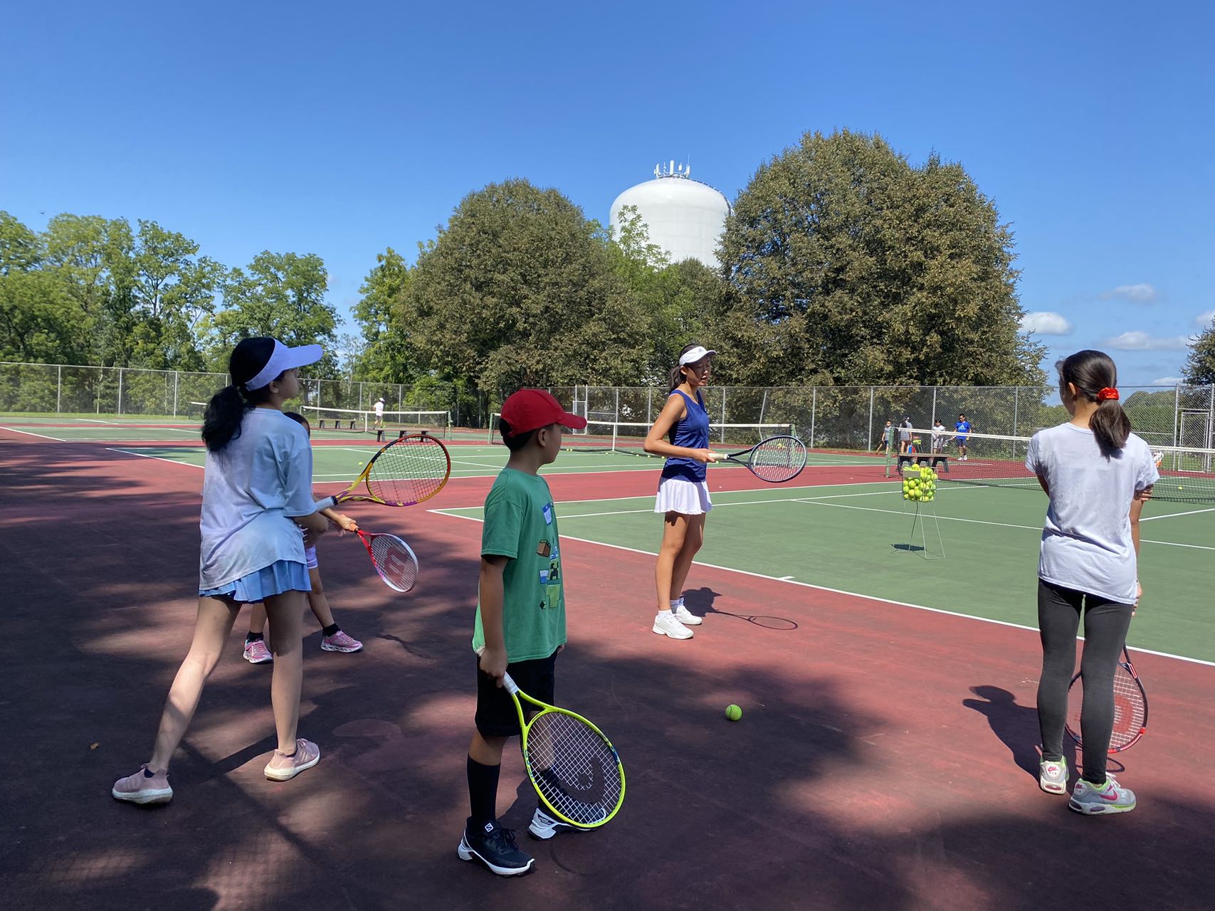 A coach teaching young players during an HXCS-LV tennis club session