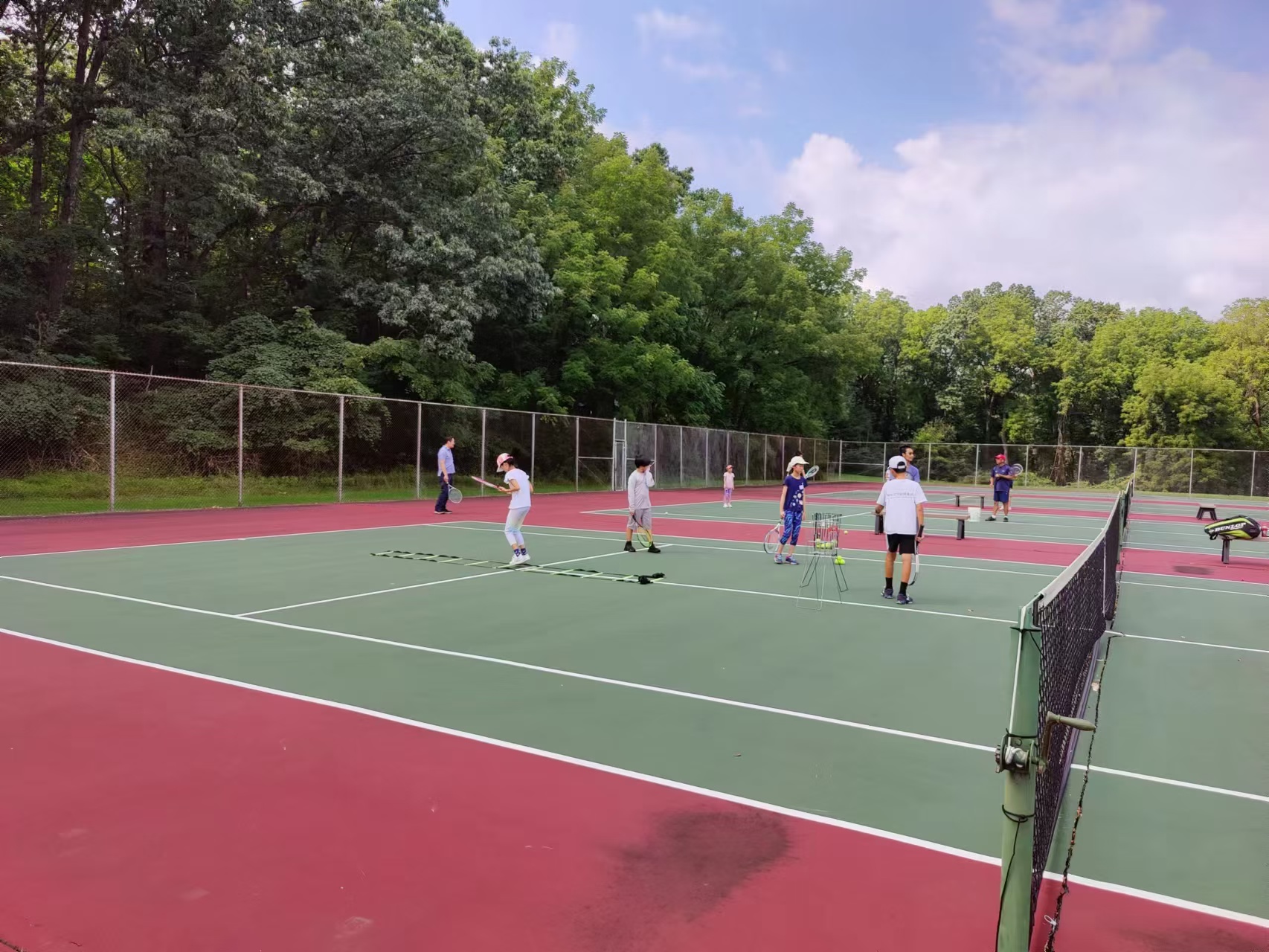 Fall tennis club players rotating through drills across the courts