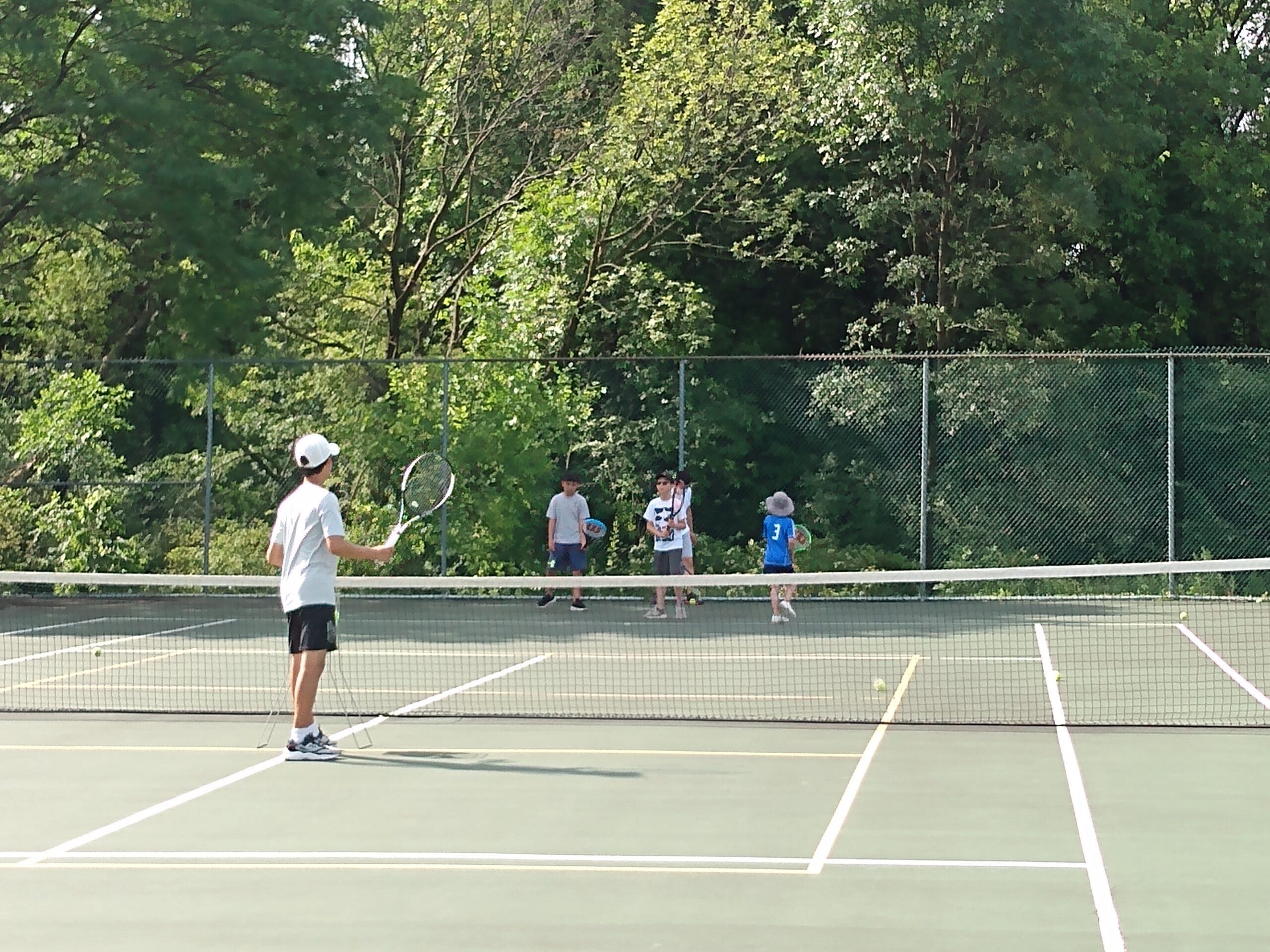 A coach feeding a ball to a young player during camp