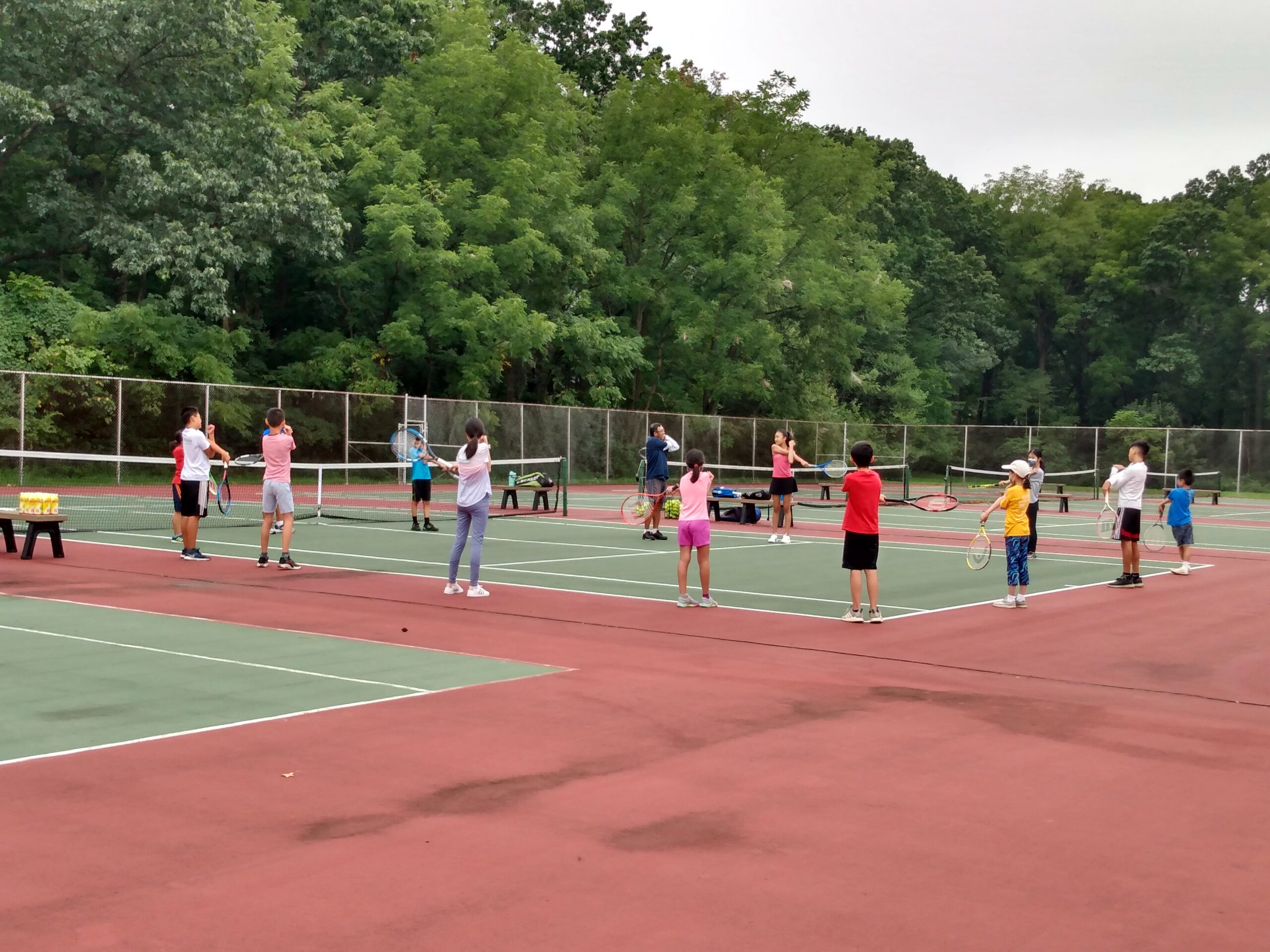 Fall tennis club players practicing in groups across the courts