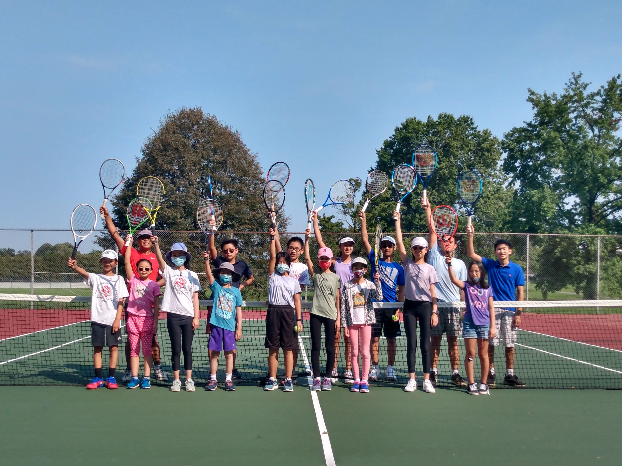 Fall 2021 tennis club players and coaches holding racquets together